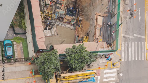 Top-down view of a busy construction site next to a street with cars, cyclists, and pedestrians