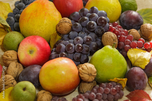 фотографія Autumn harvest assortment of fresh fruits, grapes and walnuts on rustic backgrou