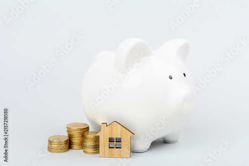 Piggy bank with house model on color background
