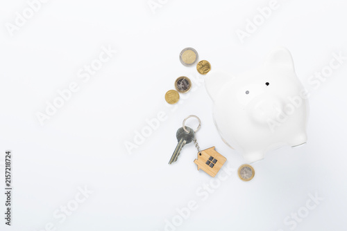 Piggy bank with house model on color background, top view