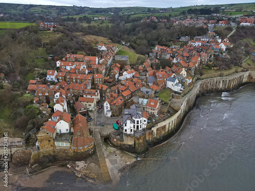 Aerial view of Robin Hood's Bay; picturesque coastal fishing village in North Yorkshire, England with red roof cottages, small harbour, scenic ocean bay in North York Moors National Park, UK
