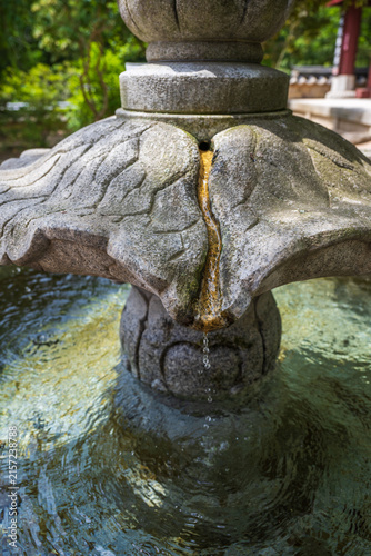 Cuadro en lienzo Pure spring water dripping from carved stone lotus fountain at traditional Korean Buddhist temple