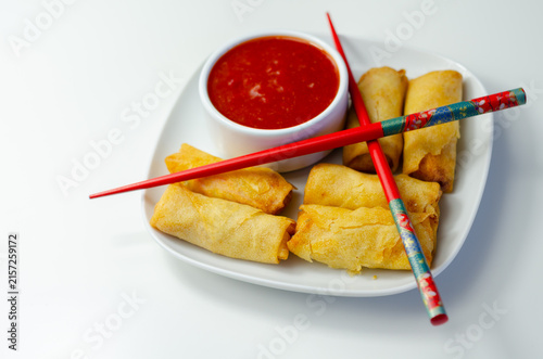 Golden spring rolls rest on a white plate