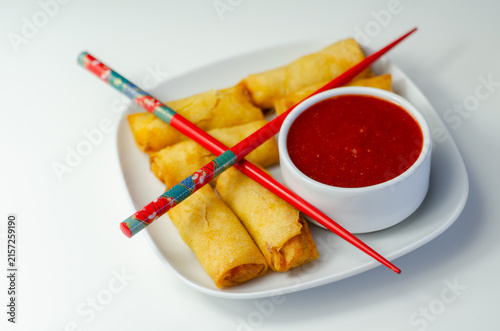 Golden spring rolls rest on a white plate