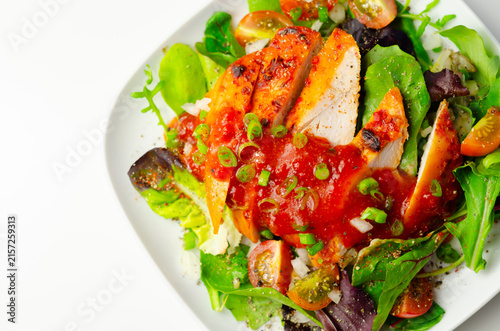 Grilled chicken slices sit atop fresh greens