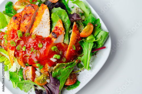 Grilled chicken slices sit atop fresh greens