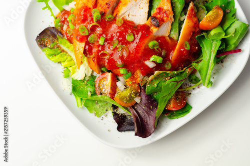 Grilled chicken slices sit atop fresh greens