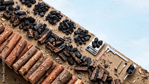 Overhead view of charcoal briquettes and stacked firewood logs