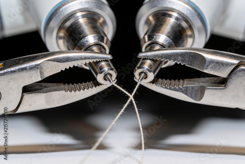 Fototapeta Tiny surgical robot instrument tips manipulating a fine suture thread