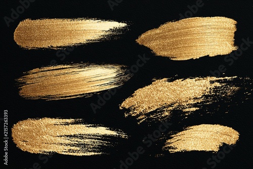 Golden watercolor brush strokes collection on black background with metallic texture for luxury design and invitation card.