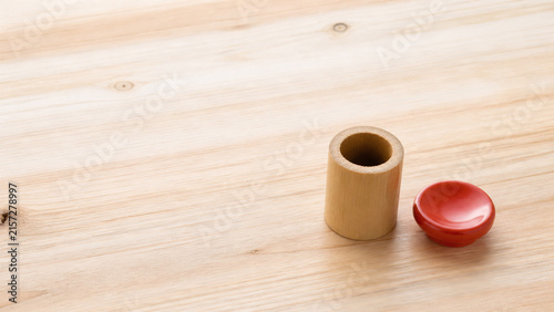 Naklejka 杉の板に並べた茶道具の蓋置 竹と朱の陶器と余白のある背景
