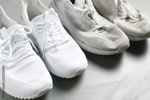 Photography New sneakers and old footwear on grey table, closeup