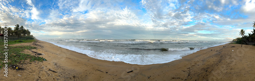 Tropical Beach with Blue Sky, Ocean Waves and Sandy Coastline Landscape, Panoramic view of a tropical sandy beach with ocean waves and dramatic clouds