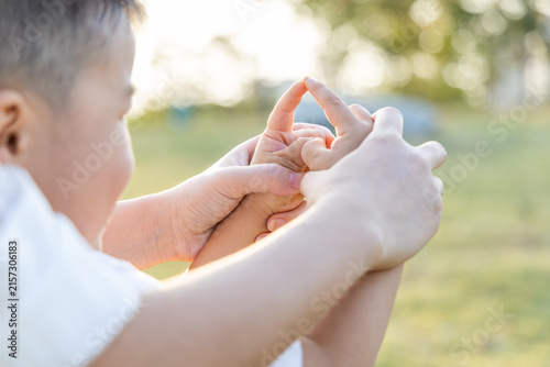 Konstfotografi A young child and an adult hold hands gently outdoors in natural sunlight, showing tender interaction