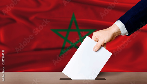 Fotografie Hand placing a ballot in ballot box with the Moroccan flag in the background
