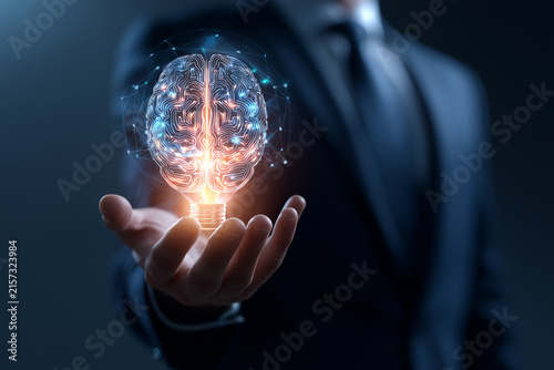 Businessman holding a glowing brain circuit light bulb