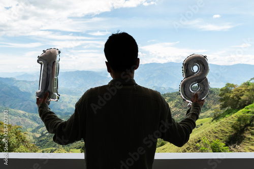 Картината върху платно Man holding 18 balloons celebrating adulthood freedom landscape