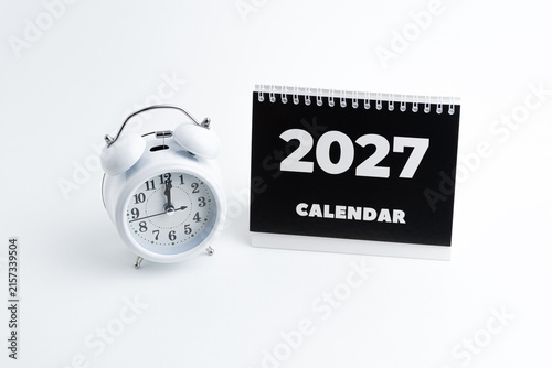 Classic white twin bell alarm clock and black 2027 desk calendar on white background