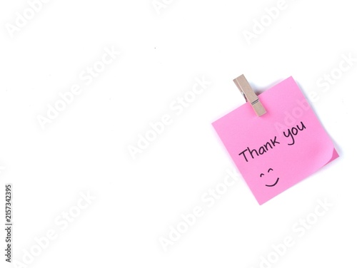 Bild auf Leinwand Thank you handwritten with happy face on a pink adhesive note clipped with wooden peg, isolated on white background