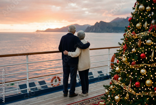 Senior couple embracing on a cruise ship deck near a christmas tree
