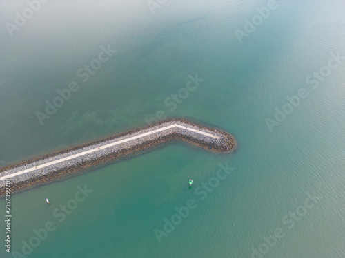Картината върху платно Aerial view of a stone breakwater in turquoise ocean water