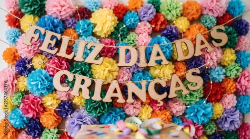 Feliz Dia Das Criancas banner with colorful paper pom poms and fairy lights celebration