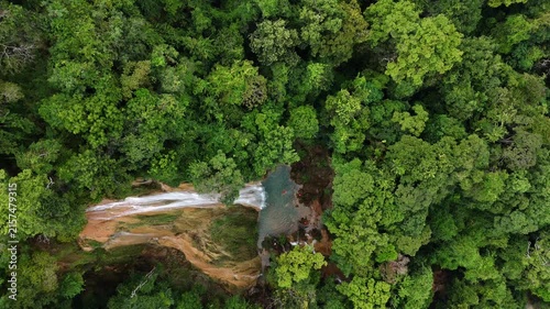 An aerial video showing a waterfall flowing from a mountain in the forest.
