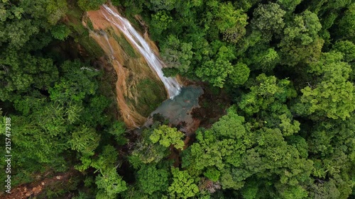 An aerial video showing a waterfall flowing from a mountain in the forest.