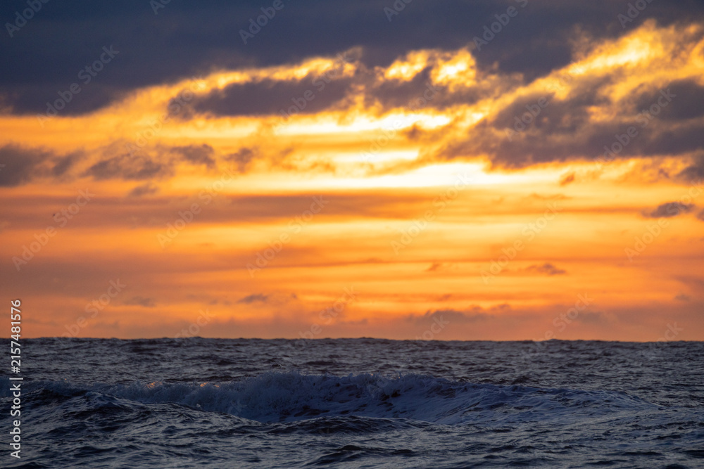 Fototapeta premium A Stunning and Impressive Sunset Over the Ocean Featuring Dramatic Cloud Patterns and Colors
