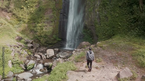 Serene Waterfall Surrounded by Lush Greenery and Rocky Terrain Captured in Daylight