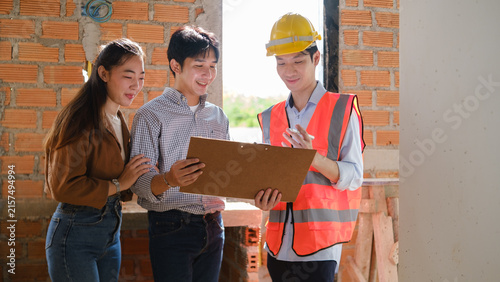 Asian construction team reviewing project plans at an unfinished building site.
