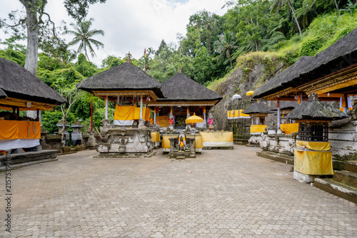 Photography BALI, INDONESIA – OCTOBER 20, 2024: Traditional thatched-roof Hindu shrines draped in yellow ceremonial cloths at Gunung Kawi Temple