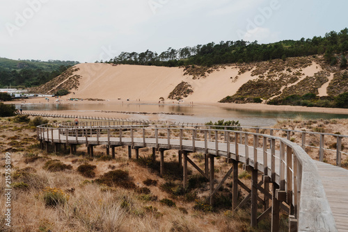 Quadro su tela Sao Martinho do Porto, Portugal Wooden boardwalk crosses coastal dunes toward the bay