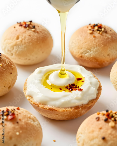 Harissa dip poured into a small edible flatbread cup, sauce visibly thick and creamy, topped with olive oil, chili flakes and toasted seeds, several miniature bread cups arranged around it