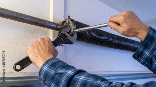 Mechanic Hands Repairing Garage Door Torsion Spring with Wrench and Winding Bar Service Concept