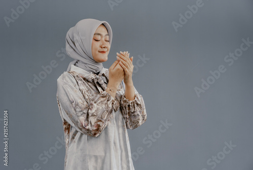 Obraz na płótnie Portrait of Asian Muslim woman praying with open arm isolated over gray background