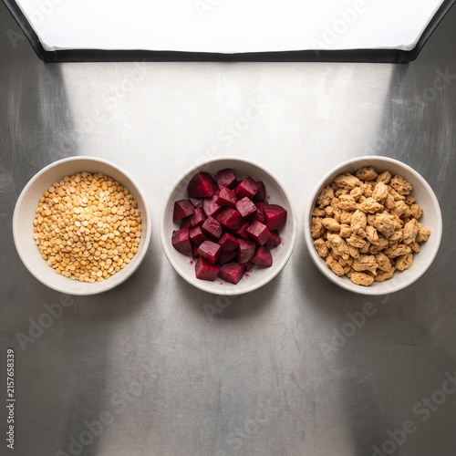 Healthy plant-based ingredients in white bowls, diced beetroot and soy protein on metal surface, vegan meal prep ingredients
