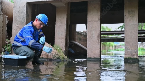 Environmental worker inspecting wastewater and collecting water samples at an industrial treatment facility