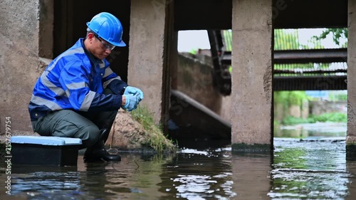 Environmental worker inspecting wastewater and collecting water samples at an industrial treatment facility