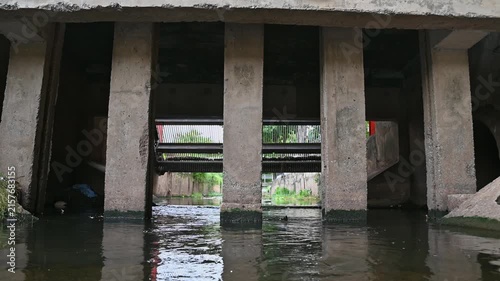 Concrete drainage channel with flowing water beneath an urban infrastructure structure