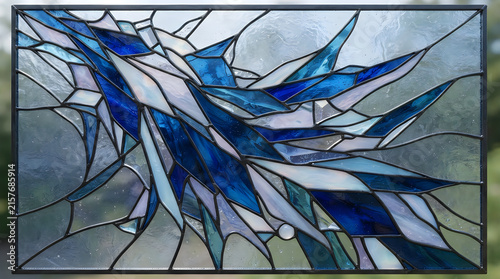 Stained glass window with vibrant blue and white abstract prism cascade design in modern interior lighting