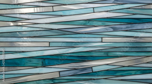 Close-up of teal glass mosaic tiles with reflective grout lines in modern geometric pattern