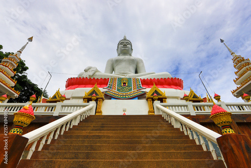 Obraz na plátne Large white seated Buddha statue on a red lotus base above stairs at a Thai temple under a blue sky