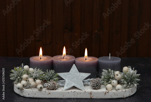 Third Sunday of Advent: Advent arrangement with berries, twigs, and three lit candles against a wooden background, with space for text.