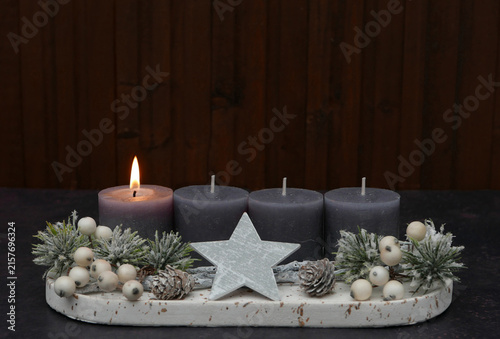 First Sunday of Advent: Advent arrangement with berries, twigs, and a lit candle against a wooden background, with space for text.