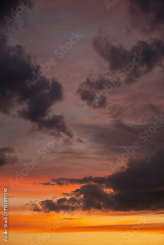 Dramatic sunset sky with dark storm clouds and glowing orange horizon.