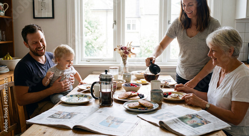 Happy multi generational family with baby grandparents and parents sitting around dining table enjoying morning breakfast meal and coffee together