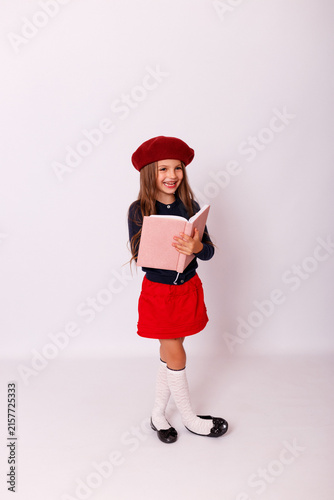 ull length portrait of happy little girl in red beret holding open notebook on white background