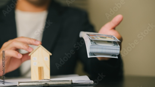 Businessman Holding Mortgage Documents with House Model and Credit Cards, Home loans or mortgages; loan approval; financial products.