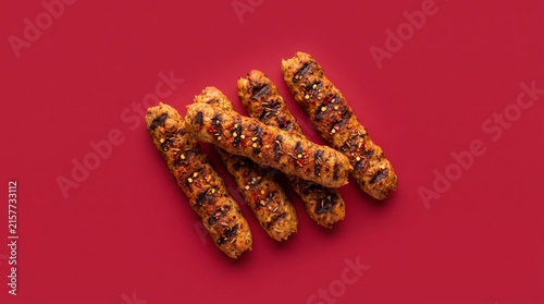 Kebab skewers sit on a bright red background.